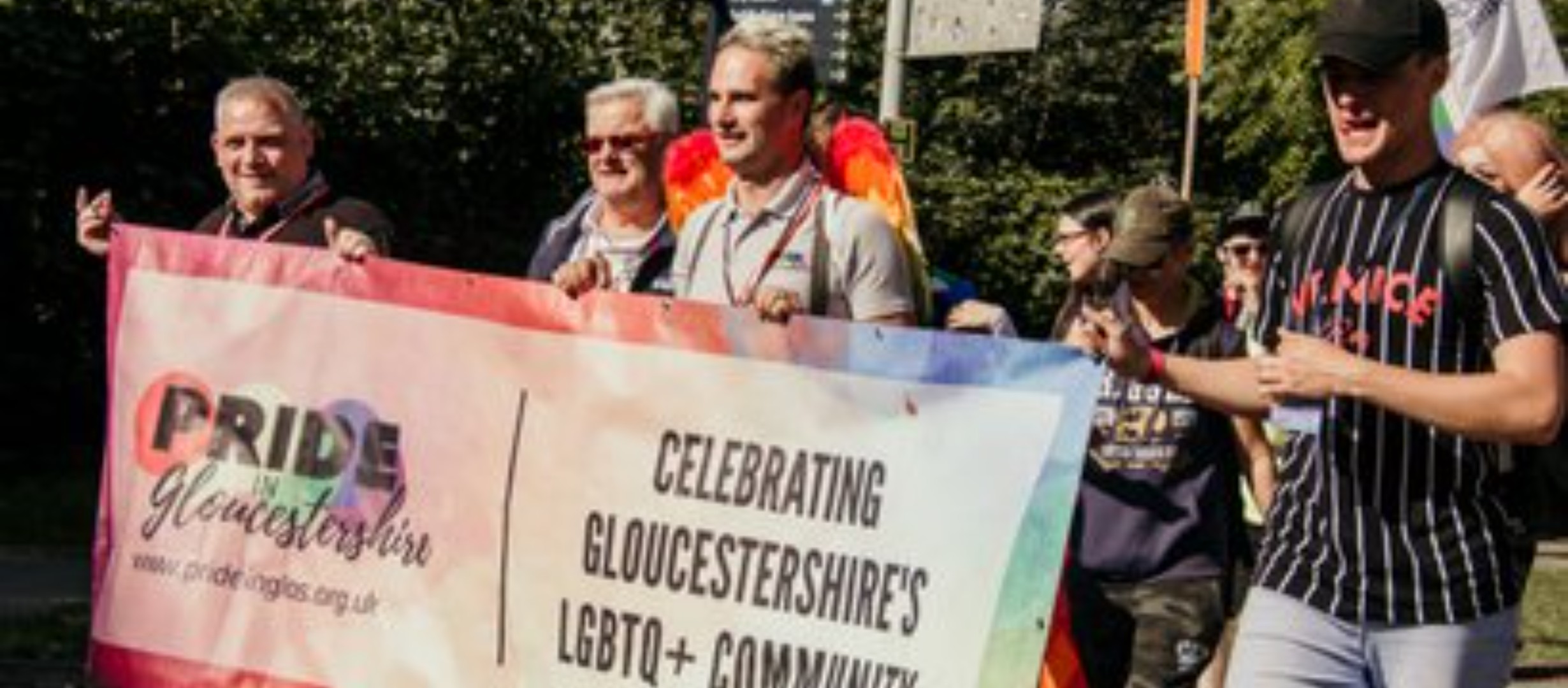 Image of Pride in Gloucestershire attendees holding a banner
