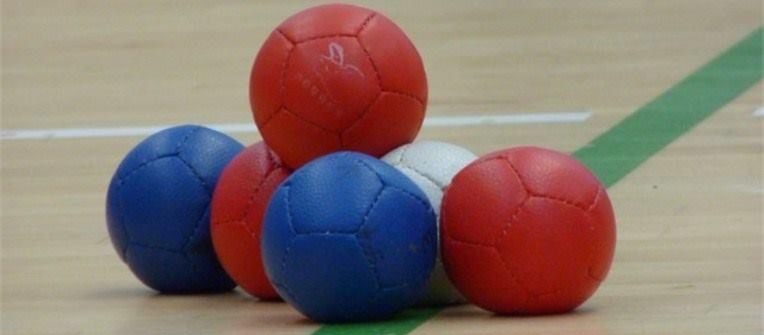 A group of 5 boccia balls, two blue, two red and one white with another red ball balanced on top