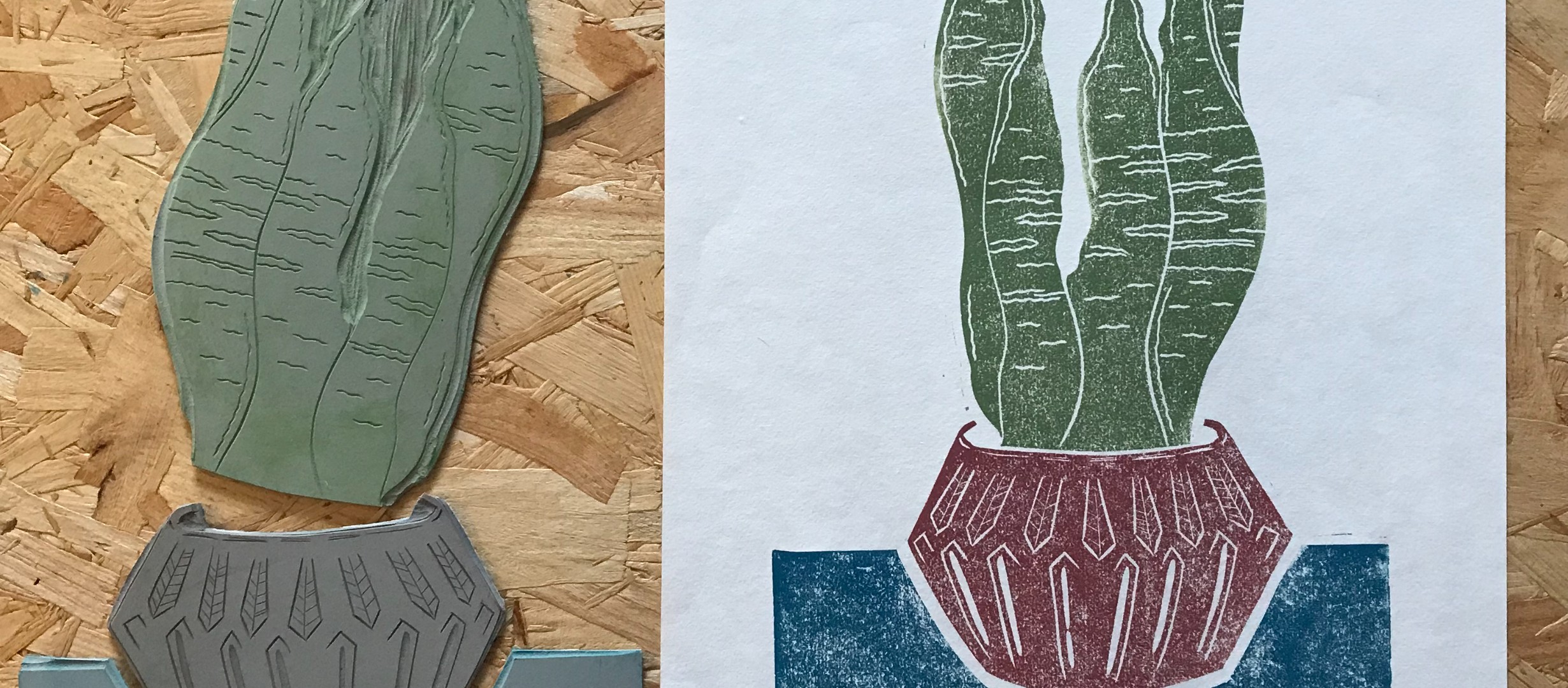 Lino stamp of a canvas in a pot next to a lino print of a green cactus in a red pot on a wooden table