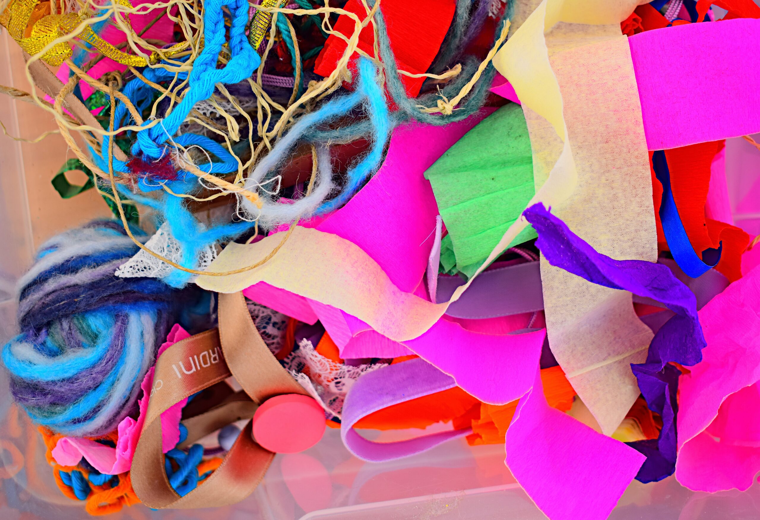 A colourful photograph of bits of scrap materials including paper, string, and other vibrant odds and ends that can be used to make interesting new art pieces