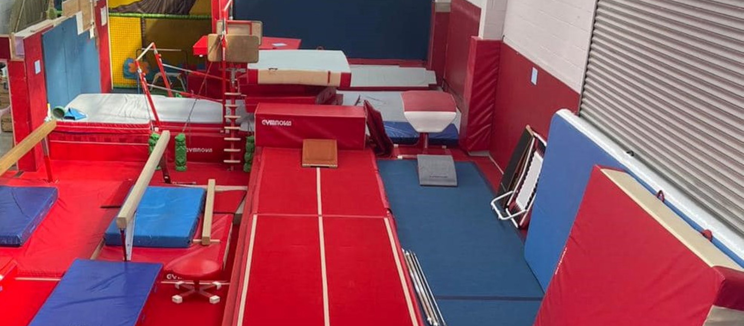 gymnasium with red and blue floor mats, bars, and other equipment