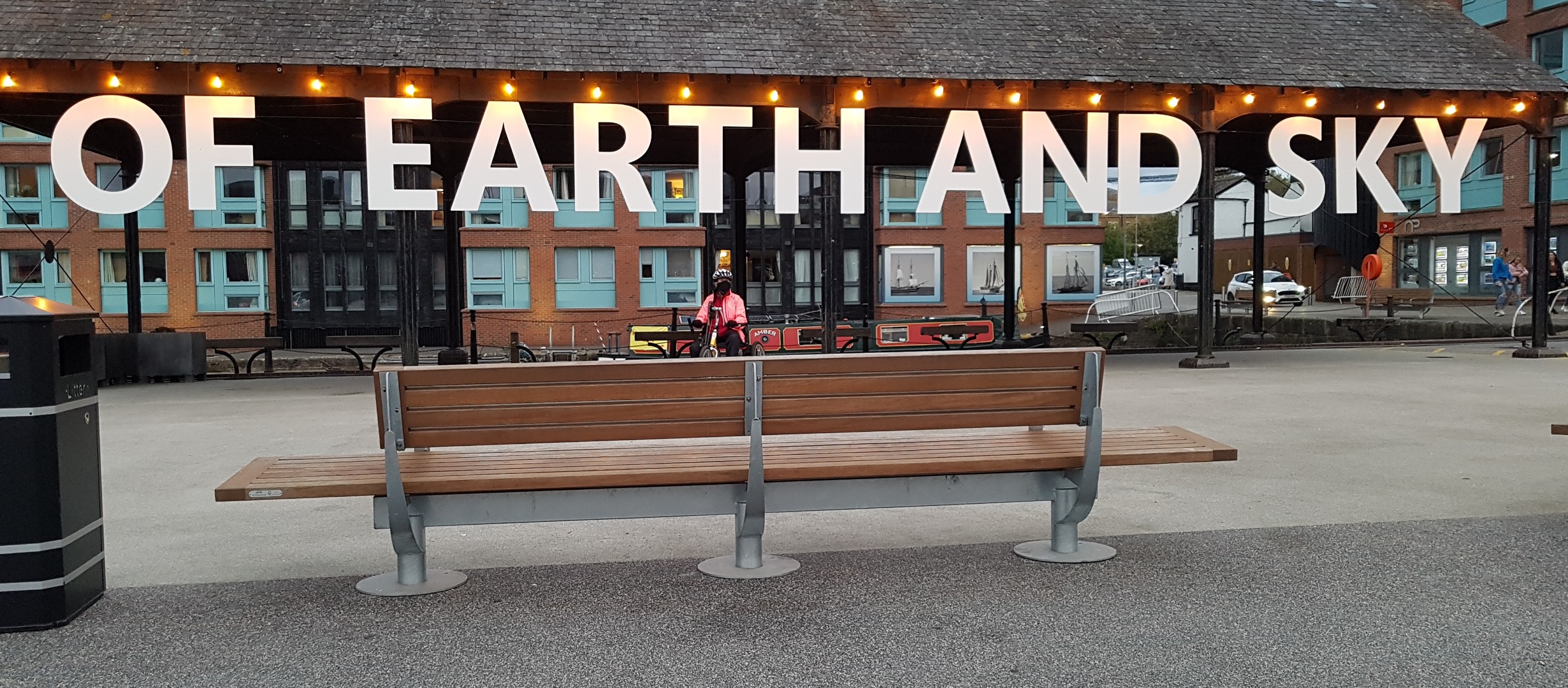bench with the words 'of earth and sky' hanging in big letters from a roof behind