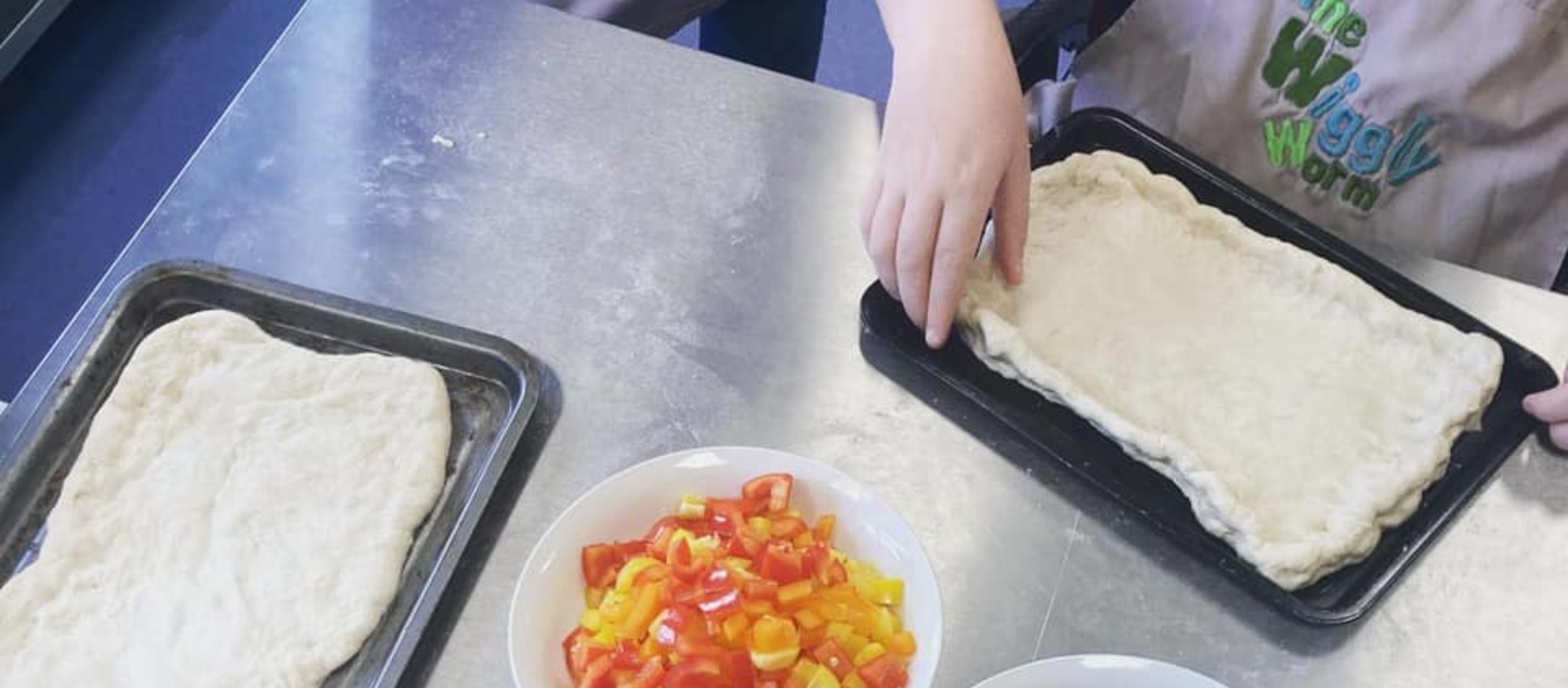 An image of someone putting peppers on pizza dough
