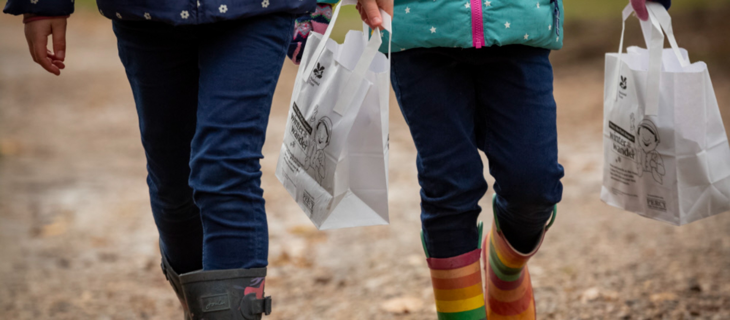 Two children carry their Percy the Park Keeper prize bags as they walk the trail