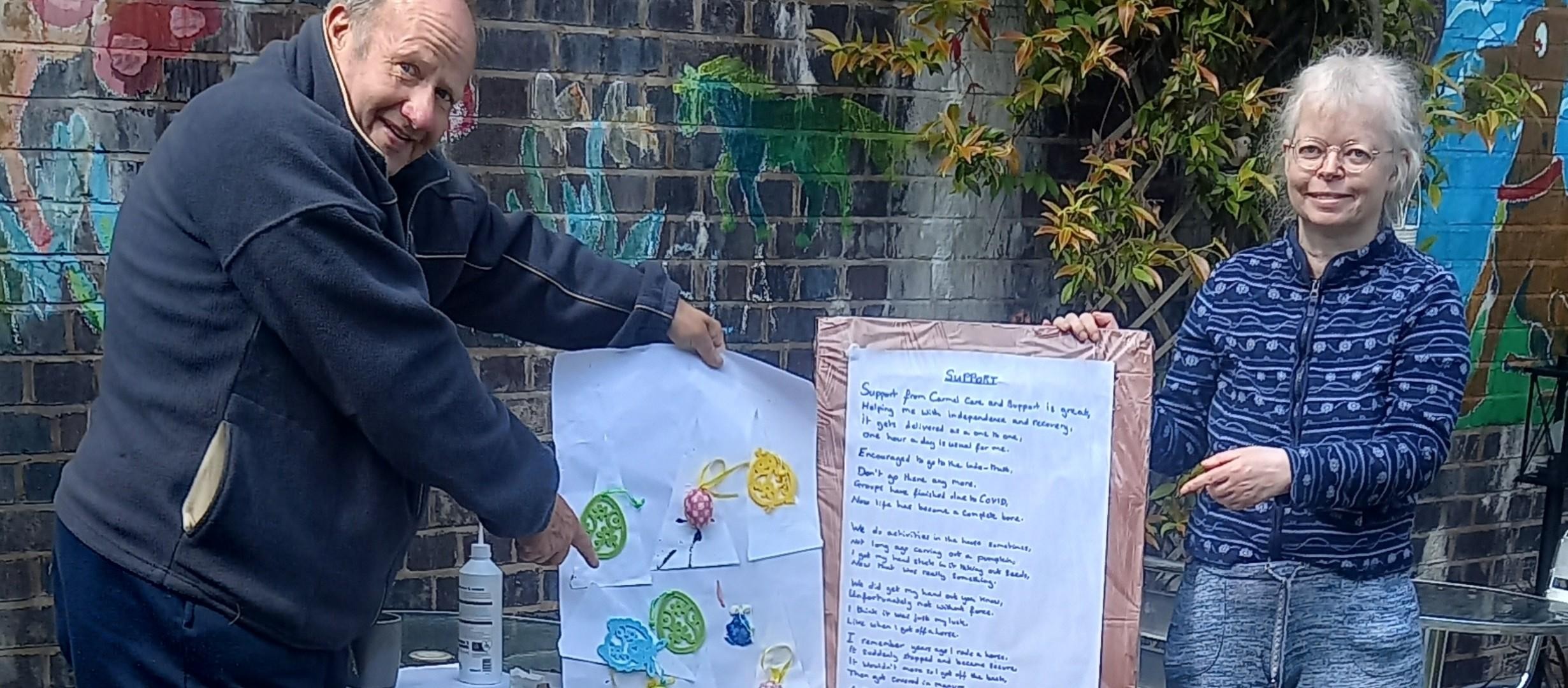 man pointing to artwork, woman pointing to poem. outside