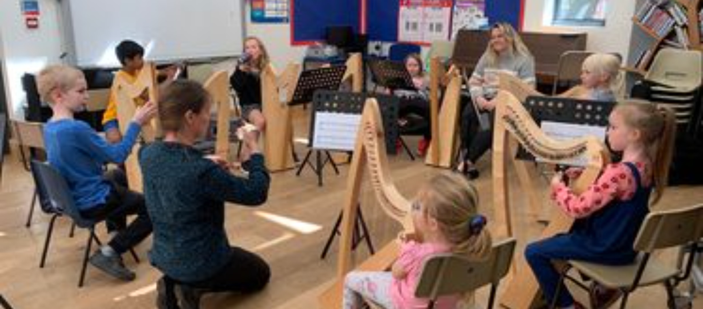 Morwenna teaching the harp to a group of children