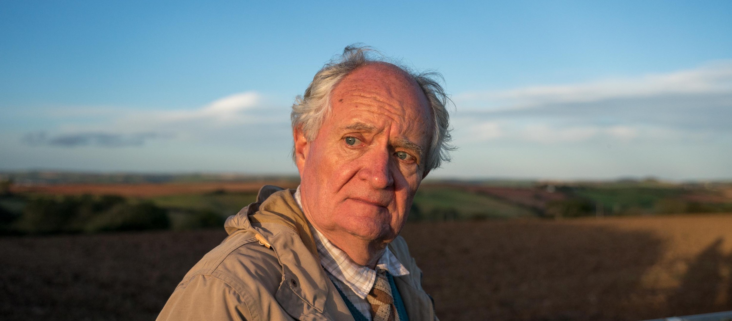 Jim Broadbent stood in a farming field