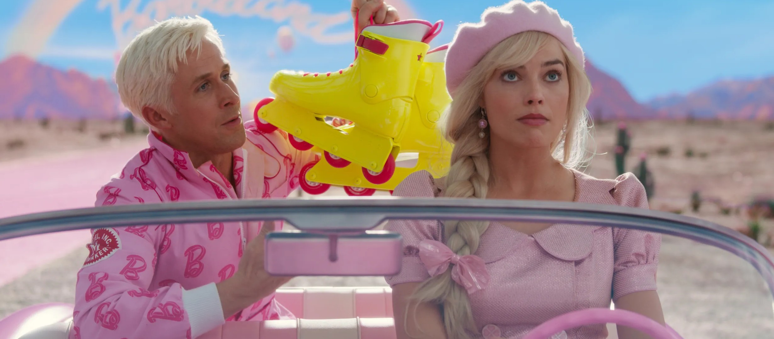 Margot Robbie as Barbie and Ryan Gosling as Ken. They are in a car and Ryan is showing Margot a pair of bright yellow roller skates 