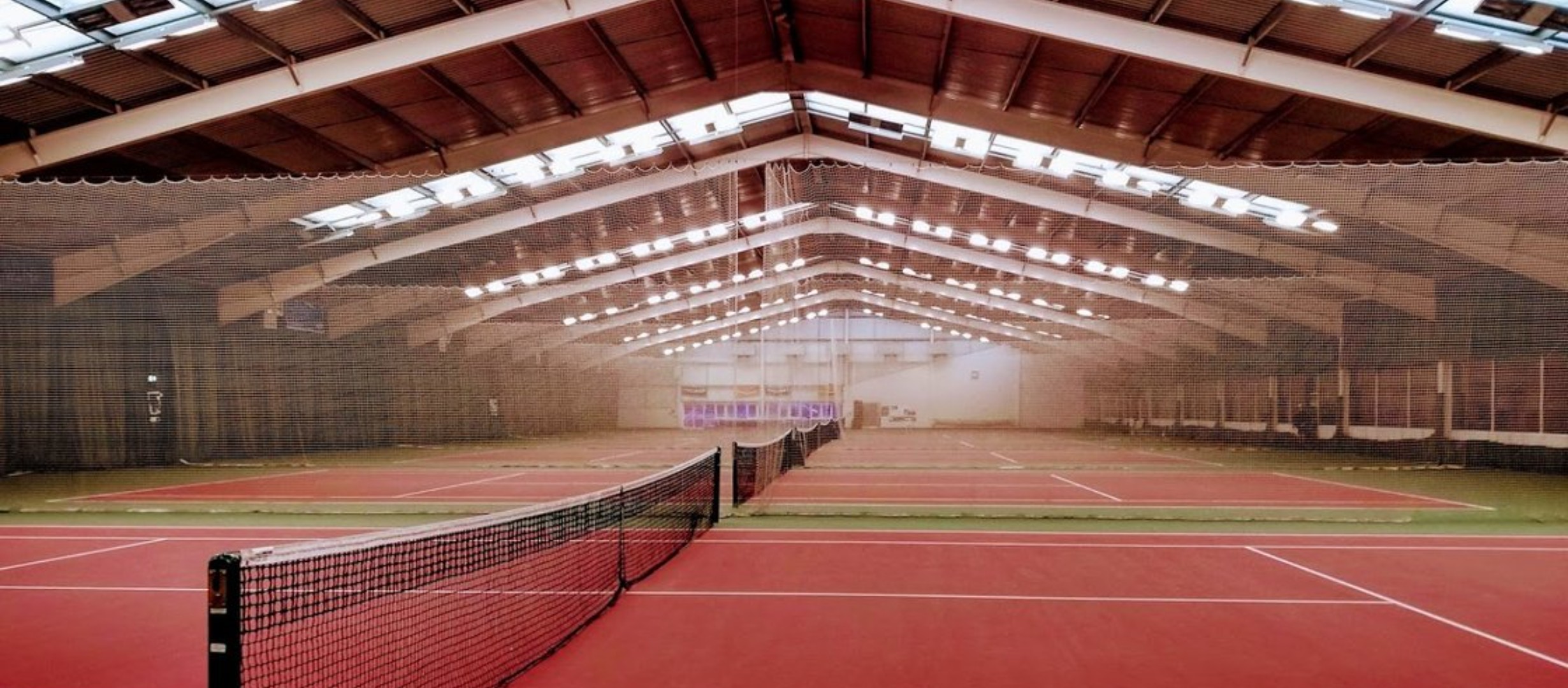 All 6 red and green indoor tennis courts with curtains drawn