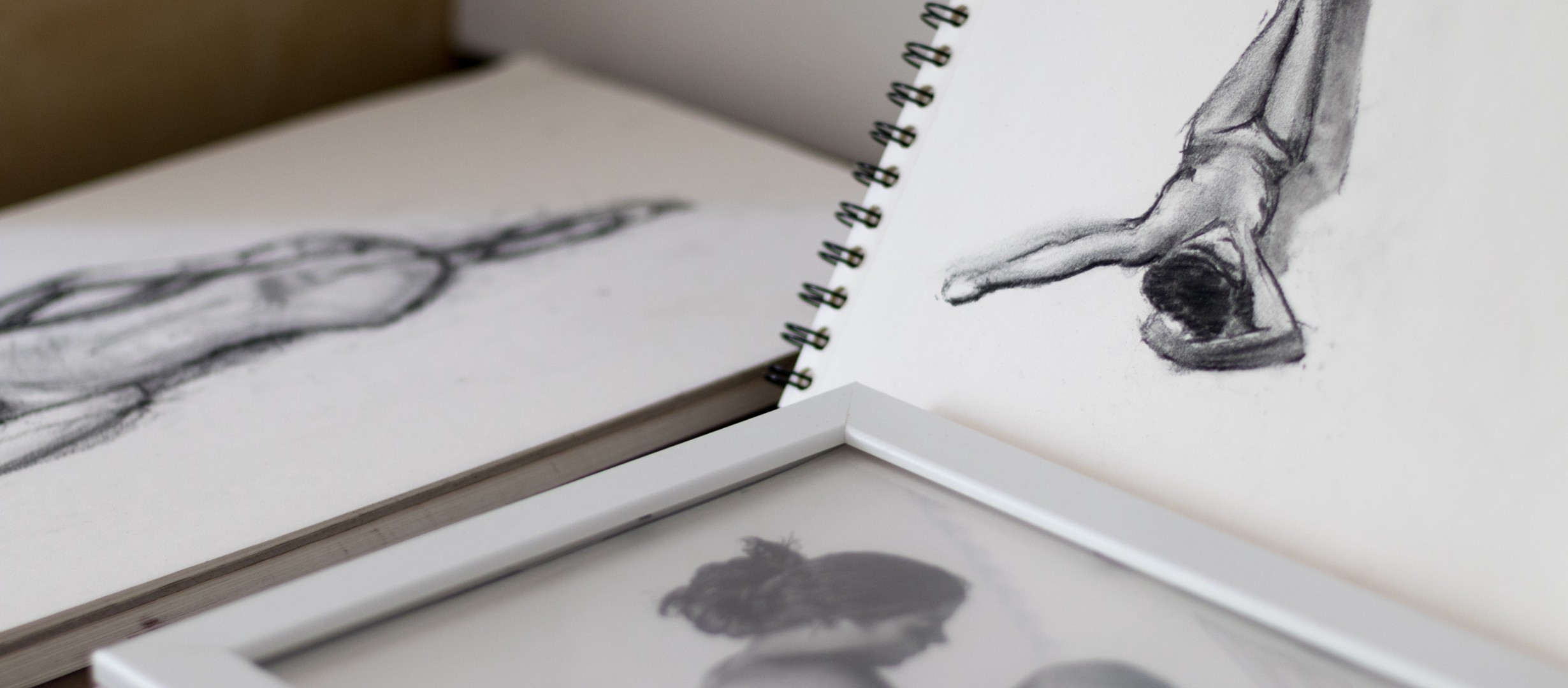Photograph of sketchbooks with pencil figure drawings in