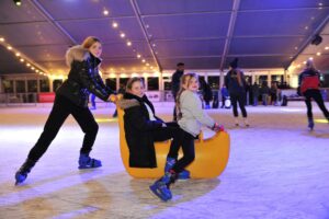 Family skating on the ice rink using a skate aid.