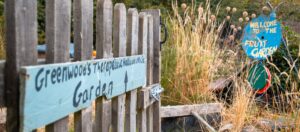 Rustic fence with hand painted sign reading Greenwoods Therapeutic Horticulture