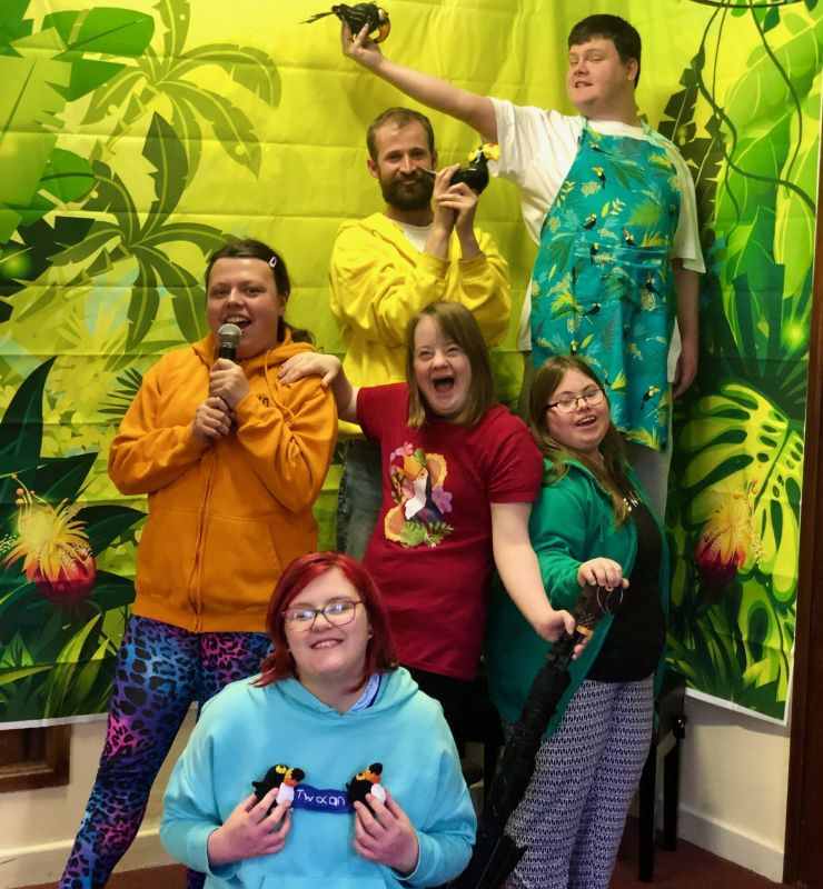 A group of young people being creative smiling and holding Toucan birds.