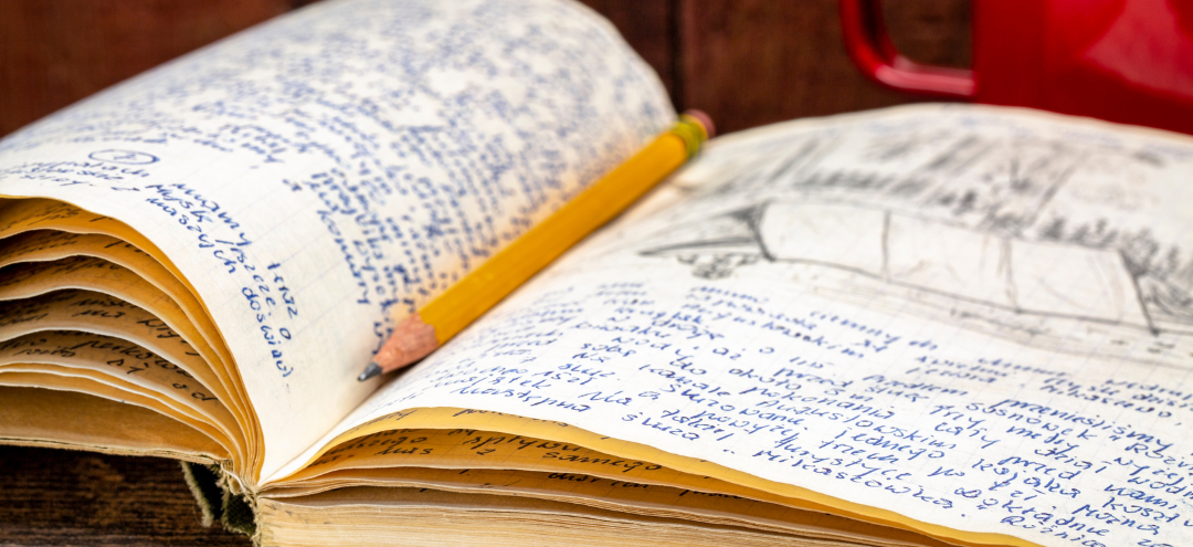 This is a photograph of an open journal with a drawing of a tent. There is a yellow pencil and a red mug