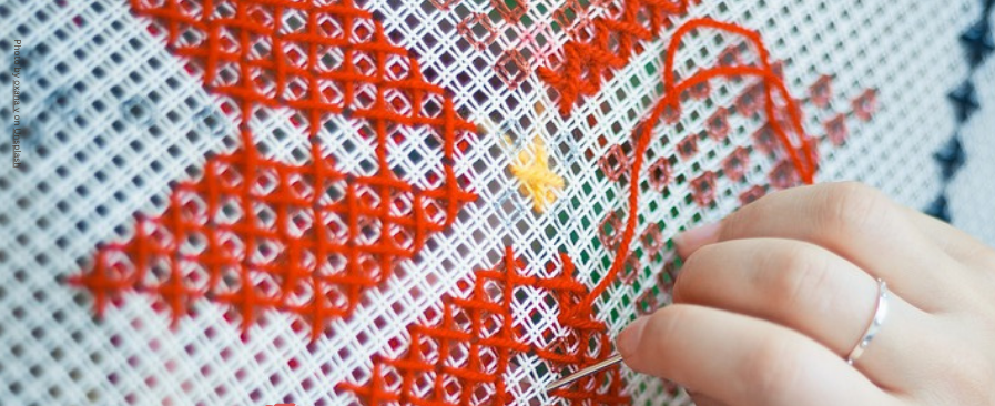 This poster has a photograph of a lady sewing a star embroidery with red thread