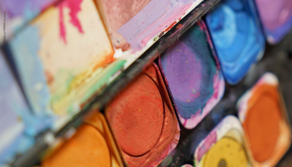 This is a photograph of a paint palette with reds, yellows, purples and blue colours