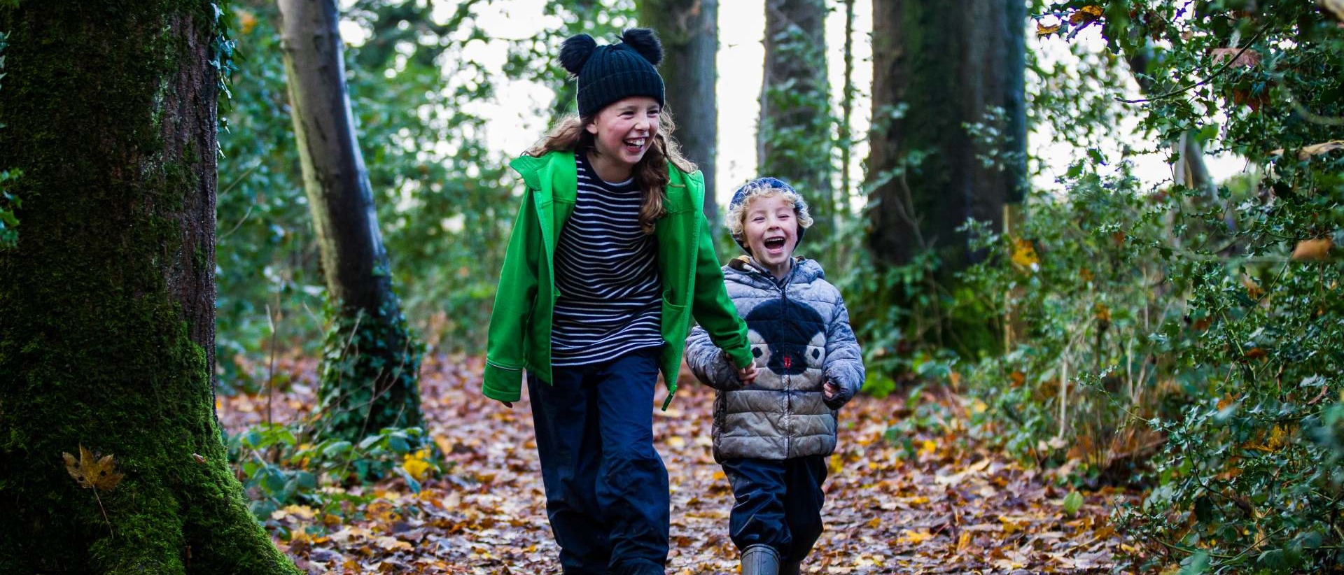 two children running through winter woodland