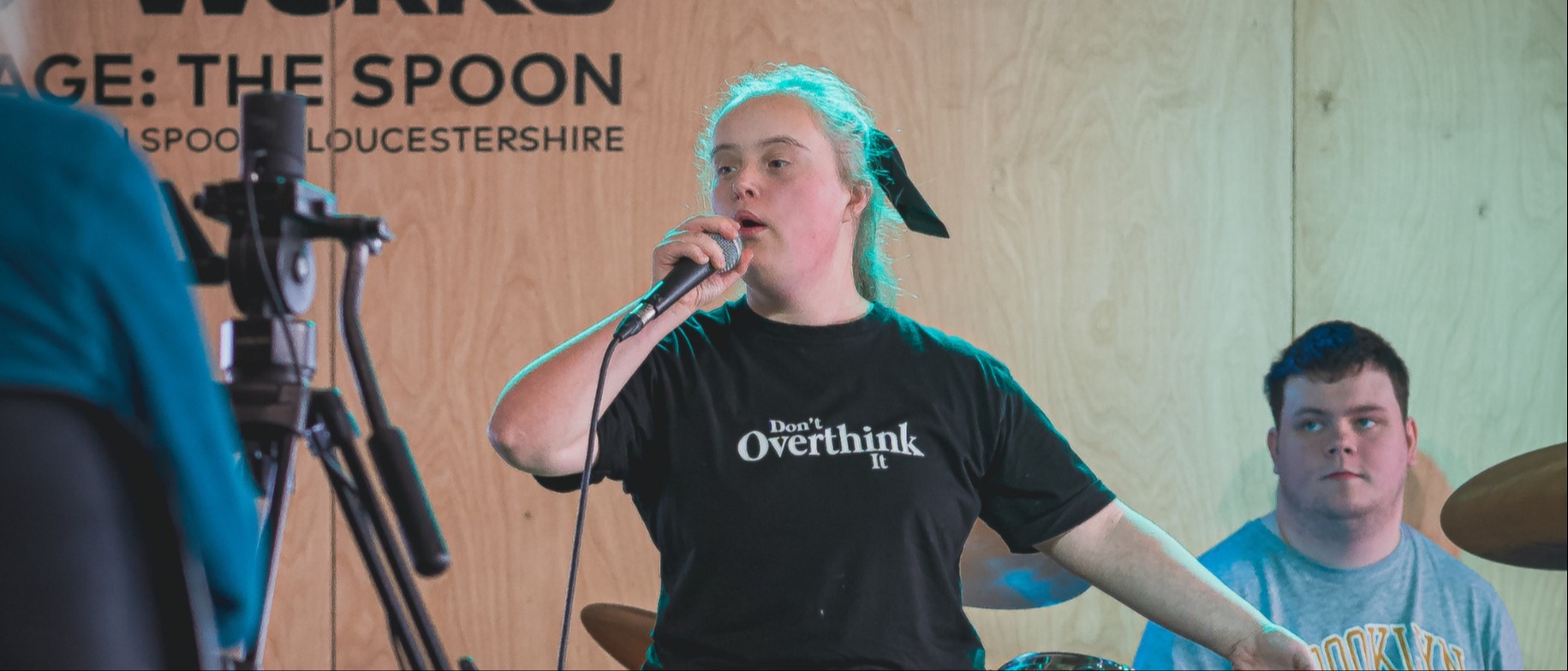 Young disabled performer singing on stage at our Hub in Gloucester