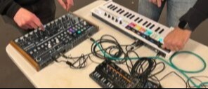 Young person using a midi controller to programme a desktop synthesizer