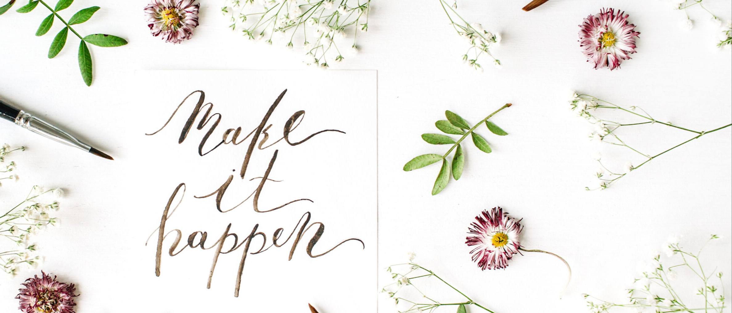 The photo is of calligraphic writing using brushes with flowers and twigs on white paper